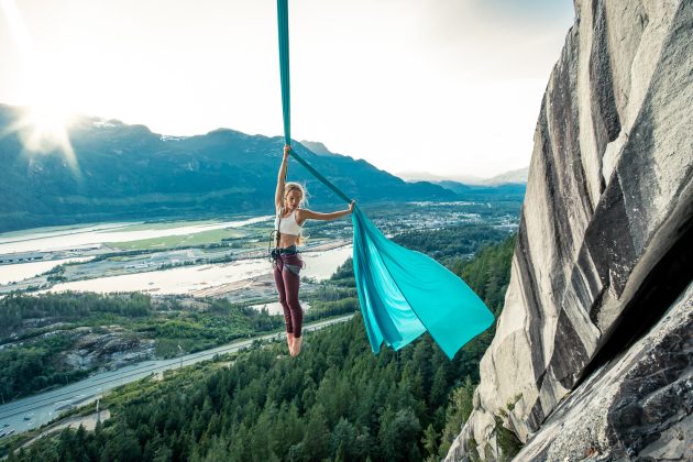 woman hanging from ribbons in the mountains