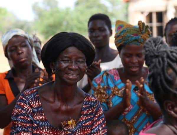 Four female women from Ghana smiling and dancing together