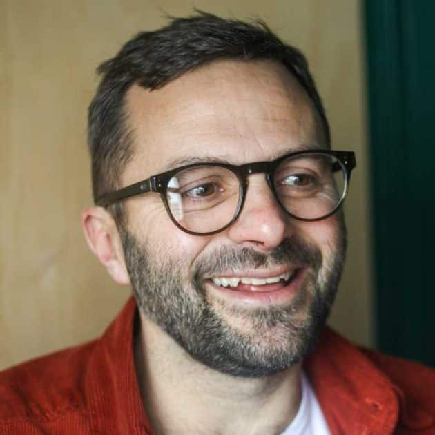 Man wearing blue light blocking glasses in a green round shape.