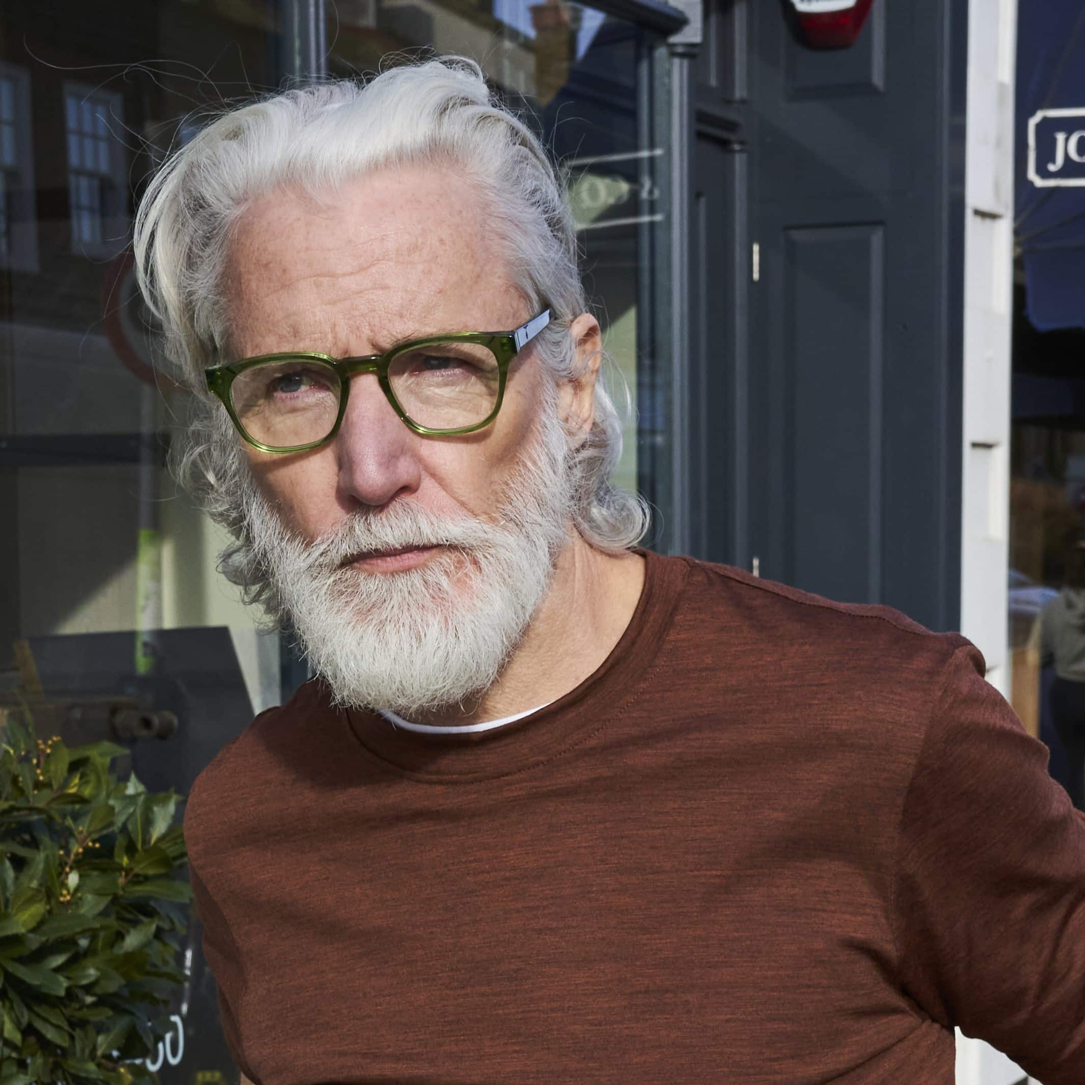 Man wearing classic square emerald green glasses with a keyhole nose bridge detail. Available with prescription or blue light lenses.