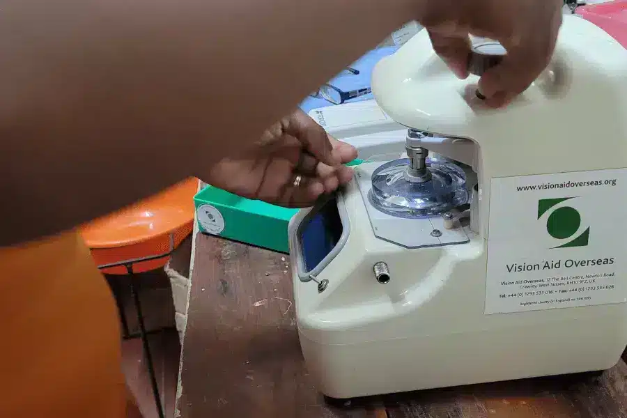 Optometrist at Chinsali vision centre cutting lenses to be fitted into a new pair of prescription glasses for Ms Konkola - local teacher.