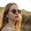 Woman wearing round metal sunglasses with green tinted high quality polarised lenses